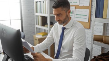 Ofiste çalışan profesyonel bir adam arka planda rafları olan belgelere odaklanarak modern kurumsal çevreyi öneriyor..