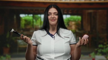 Barışçıl şehirde elinde makyaj fırçası ve sünger tutan bir kadın gösterişli güzellik odağı oluşturuyor..