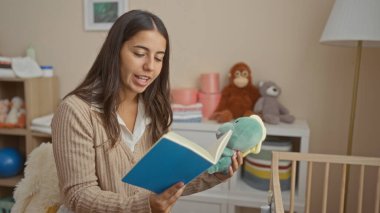 Sıcak yatak odasında oyuncaklarla masal kitabı okuyan bir kadın sıcak ve davetkar bir atmosfer yaratıyor..