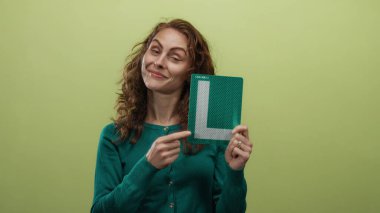 Tabağı sarı arka planda tutan kadın, öğrenme ve güvenini ifade ediyor neşeli bir gülümseme ve düşünceli jestlerle, izole edilmiş ve yeni deneyimlere hazır..