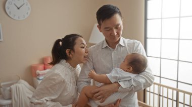 Anne ve baba yatak odasındalar. Çocuklarını sıcak aile evlerinde sevgiyle kucaklıyorlar. Mutluluk ve sıcaklığı yansıtıyorlar..