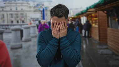 Çarşıdaki genç İspanyol adam bulutlu gökyüzünün altında duygularıyla ağlıyor. Etrafı hareketli mağazalar ve şehir hayatıyla çevrili. Günlük mavi kapüşonlu kazakla süslenmiş..