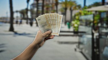 Şehir dışındaki bir restoranın terasında elinde Danimarka kronu banknotları tutan bir adam sokakta kahve içerek bir anlık finansal işlemleri ve kentsel yaşam tarzını yakalıyor..