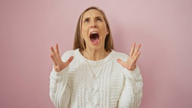 Pembe arka planda, beyaz kazak giyen, hayal kırıklığına uğramış sarı saçlı bir kadın bağırıyor..