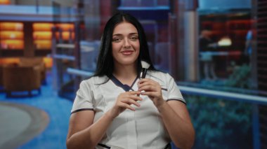 Üniformalı bir kadın lüks otel ortamında fırça tutuyor, rahat ve profesyonel bir konukseverlik havası var ve arka planda zarif bir dekor var..