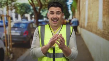 Şehir caddesinde yansıtıcı yelek giymiş İspanyol bir adam. Bulanık arabalar ve ağaçlarla dolu bir şehir ortamında gönüllü ruhu somutlaştırıyor..