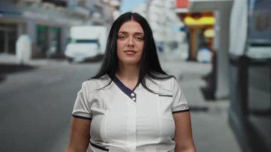 Kadın şehir sokaklarında güven içinde el kol hareketi yapıyor, günlük kıyafetlerini giyerken çeşitlilik ve vücut pozitifliği gösteriyor, kentsel çevre ile sorunsuz bir şekilde harmanlıyor..