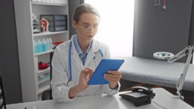 Doktor, klinik ortamdaki tablet verilerini inceliyor. Etrafında tıbbi ekipmanlarla laboratuvar önlüğü giymiş odaklanmış genç bir kadını gösteriyor..