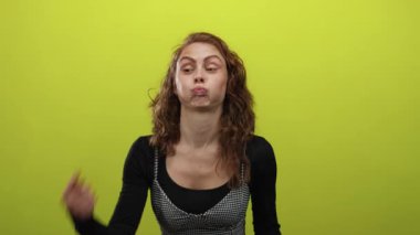 Parlak sarı arka planda parmakları olan komik suratlı bir kadın, mizah ve neşe ifade ediyor, gençlik enerjisini ve neşesini somutlaştırıyor..