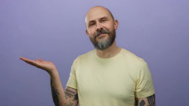 Dövmeleri olan beyaz sakallı bir adam, izole edilmiş mor bir arka plana gülümserken elini açacağını gösteriyor.