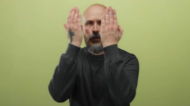 Sakallı adam yeşil arka planda esprili ve şaşırtıcı dövmeler gösteriyor..