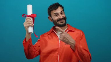 Turuncu üniformalı bir adam gülümsüyor mavi arka planda diploması var. Cezaevinde eğitimi simgeliyor..