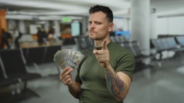 Elinde dolarlarla havaalanı terminalini işaret eden ve zenginliği ve seyahati sembolize eden genç adam..