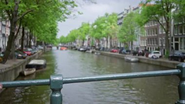 Yeşil ağaçların ve park halindeki arabaların bulunduğu Amthe Kanalı 'nın bulanık görüntüsü şehrin ikonik su yollarını ve canlı doğasını gözler önüne seriyor..