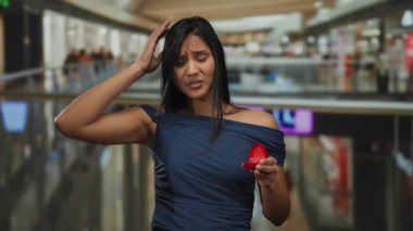 Yüzük kutusunu kapalı bir alışveriş merkezinde tutan genç kadın şaşırmış görünüyor.