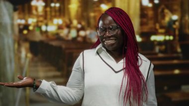 Geniş bir el ile gülümseyen bir kadın loş bir kilisede ahşap sıralarla, olumlu ve hoş bir atmosfer sergiliyor..