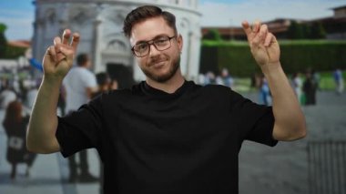 İtalya 'da sidik kulesinin önünde barış işareti yapan, arka planda kalabalık olan gözlük takan, seyahat ve turizm havası gösteren sakallı genç bir adam.