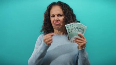 Mavi arka planda Çin Yuanı banknotları tutan kadın izole duvarın arkasında orta yaşlı görünmekten tiksindiğini ifade ediyor..
