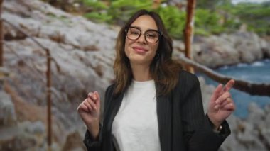 İspanyol kadın sahilde neşeyle dans ediyor kayalık bir kumsal zeminiyle, doğadaki kaygısız bir anın özünü yakalıyor..