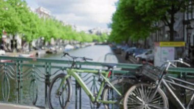 Köprüde park halindeki bisikletler, Amsterdam Kanalları 'nın canlı kentsel manzarasını yansıtıyor..