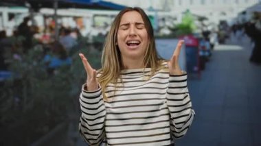 Açık hava restoranının terasında duygularını elleriyle ifade eden, hareketli sokak sahneleriyle çevrili, şehir ortamında samimi anlar yakalayan bir kadın..