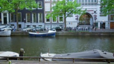 Tekneler ve tarihi binalarla bulanık amfi kanal sahnesi, zengin, odakları çözülmüş görüntülerle Hollanda kentsel ortamını yakalıyor..