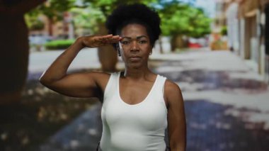 Şehir manzarası ve ağaçlarla çevrili, hareketli bir şehir caddesinde kendine güvenen bir kadın selamlıyor..