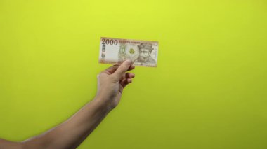 İnsanoğlu canlı sarı arka plana karşı Macar forint banknotuna sahip, izole edilmiş bir ortamda para ve finans kavramlarını sergiliyor..