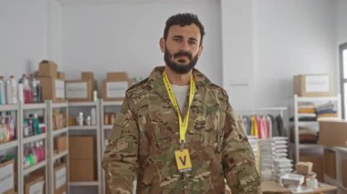 Sakallı, asker üniforması giyen İspanyol bir adam. Gönüllü olarak malzeme dolu bir odada başparmak işareti veriyor. Kapalı alanlara yardım etmeye hazır olduğunu gösteriyor..