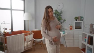 Sıcak bir yatak odasında beşiğiyle gülümseyen hamile bir kadın barışçıl ve besleyici bir çevreye önem veriyor..
