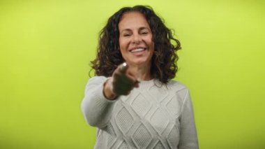 Parlayan sarı arka planda gülümseyen bir kadın, kendine güveni olan, kıvırcık saçlı, kendine güvenen bir tavır sergiliyor.