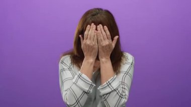 Canlı mor bir arka plan önünde şaşkınlığını ifade eden, gözlüklü, desenli gömlekli, yanaklı, yalnız ve neşeli bir kadın..