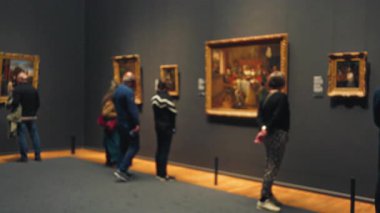 İnsanlar müze resimlerini kapalı alanlarda bulanık odak eşliğinde keşfediyor. Bokeh efektlerini vurguluyor, resimlerini sergiliyor ve farklı bir grup kültür ve yaratıcılığı takdir ediyor..