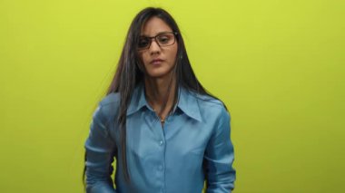 Mavi gömlekli genç bir kadın, izole edilmiş sarı arka plana karşı hareketli, tetikte veya tetikte, modern kripto para birimi ve dijital finans kavramlarını sembolize ediyor