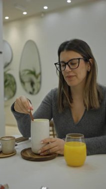 Modern lüks bir restoranda kahveden zevk alan bir kadın şık bir iç mekanı olan ve elinde büyük bir bardak portakal suyu ile sıcak bir içecek tutan bir kadın..