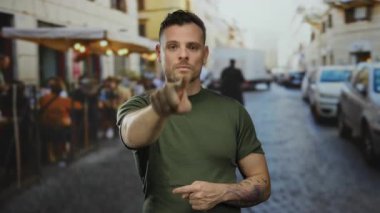 Yeşil tişörtlü bir adam canlı şehir caddesini gösteren dövmeli bulanık insanlar ve arka planda odak ve açık havada etkileşim gösteren araçlar..