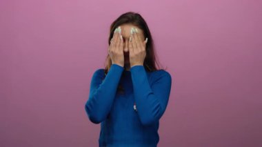 Oy kartı olan genç bir kadın, Amerika Birleşik Devletleri seçimlerinde oy verdikten sonra neşeli ifadeler ve neşeli ruh hali gösteren pembe arka planda komik suratlar yapıyor.