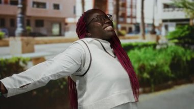 Kadın, kollarını açmış, gözlük takmış, beyaz elbiseler giymiş güneşli bir günde mutluluk ve özgürlük sergiliyor..