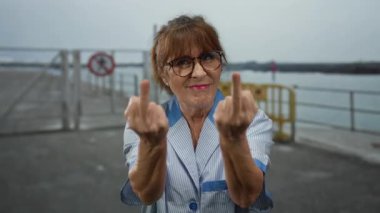 Sahil kenarında gülümseyen bir kadın orta parmak jest gözlüğü dışarıda, plajda, İspanyol asıllı son sınıf öğrencisi..