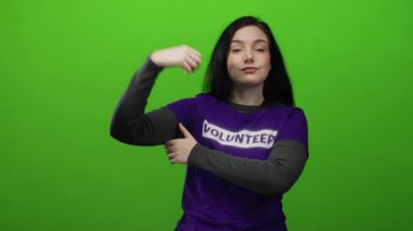 Gönüllü olarak yeşil arka planda poz veren kadın, toplumu güçlendirmeyi ve gücü simgeliyor..