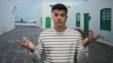 Şehir sokaklarında beyaz binalar ve yeşil kapılarla çizgili süveter giyen düşünceli ya da kafası karışmış genç bir adam..