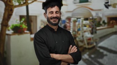 Siyah üniformalı, kendine güvenen İspanyol aşçı. Canlı bir sokakta gülümsüyor. Piyasa geçmişi ve yerel mimarisi bulanık.