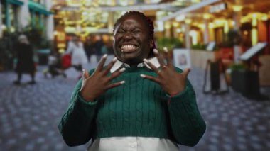 Kalabalık şehir sokak ortamında tutkuyla bağıran bir kadın, bulanık kentsel geçmişe sahip yeşil bir kazak giyiyor, hayal kırıklığını ya da öfkeyi ifade ediyor, heyecan verici duyguları canlı bir şekilde ifade ediyor..