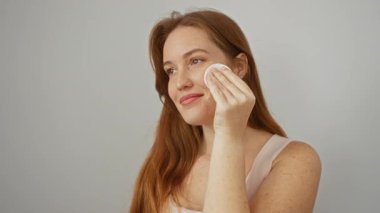 Beyaz arka planda pamuklu bez ile deriyi temizleyen kadın, cilt bakımını sağlıklı cilt için doğal ürünlerle birlikte, yumuşak cilt rutinini gösteriyor..