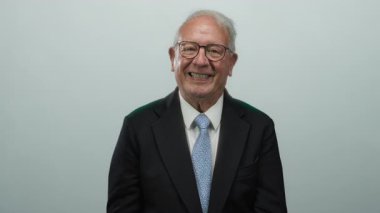 Takım elbiseli kıdemli bir adam beyaz arka plana bakıp gülümsüyor, izole bir ortamda güven ve profesyonellik yayıyor..