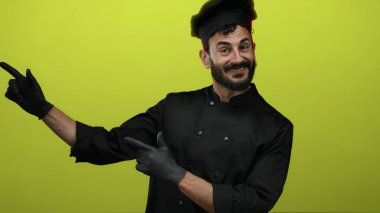 Siyah eldiven ve üniforma giyen İspanyol erkek aşçı. Her iki elinde de parlak sarı bir arka plan var. Kendine güveni ve cazibesi var..