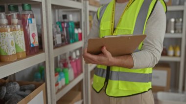 Yansıtıcı yelek giyen bir adam bağış merkezinde pano tutuyor. Gönüllü iş sırasında dağıtım malzemelerini düzenliyor.