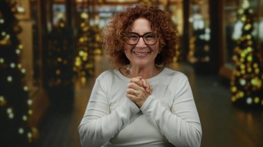 Bayram sezonunda şehir caddesinde Bokeh ışıkları altında neşeli ve davetkar bir atmosfer yaratan neşeli bir kadın..