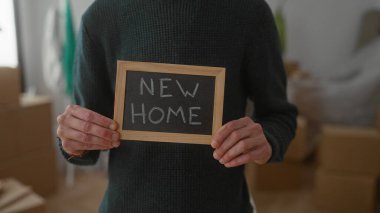 Evin içinde duran bir adam, yeni bir eve ya da daireye taşınacağını belirten kutuların arasında 