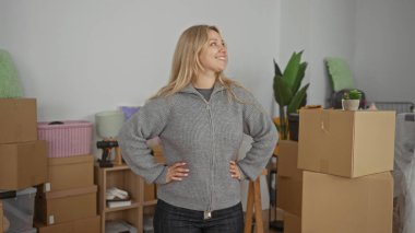 Karton kutularla çevrili yeni evdeki bavulları açan kadın modern bir daireye taşındığını gösteriyor..